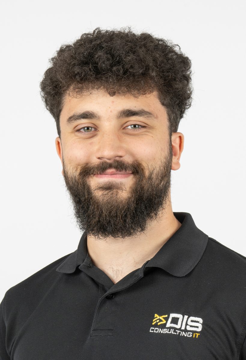 Smiling Callum Morancie from DIS Consulting IT wearing a black DIS Consulting IT polo shirt, standing against a plain light background.
