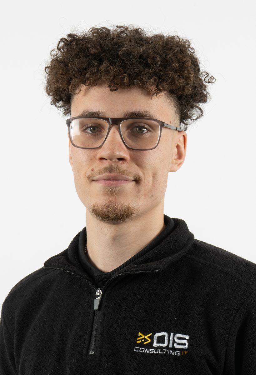 Ethan Watkins wearing glasses and a black DIS Consulting IT fleece, standing against a plain light background.