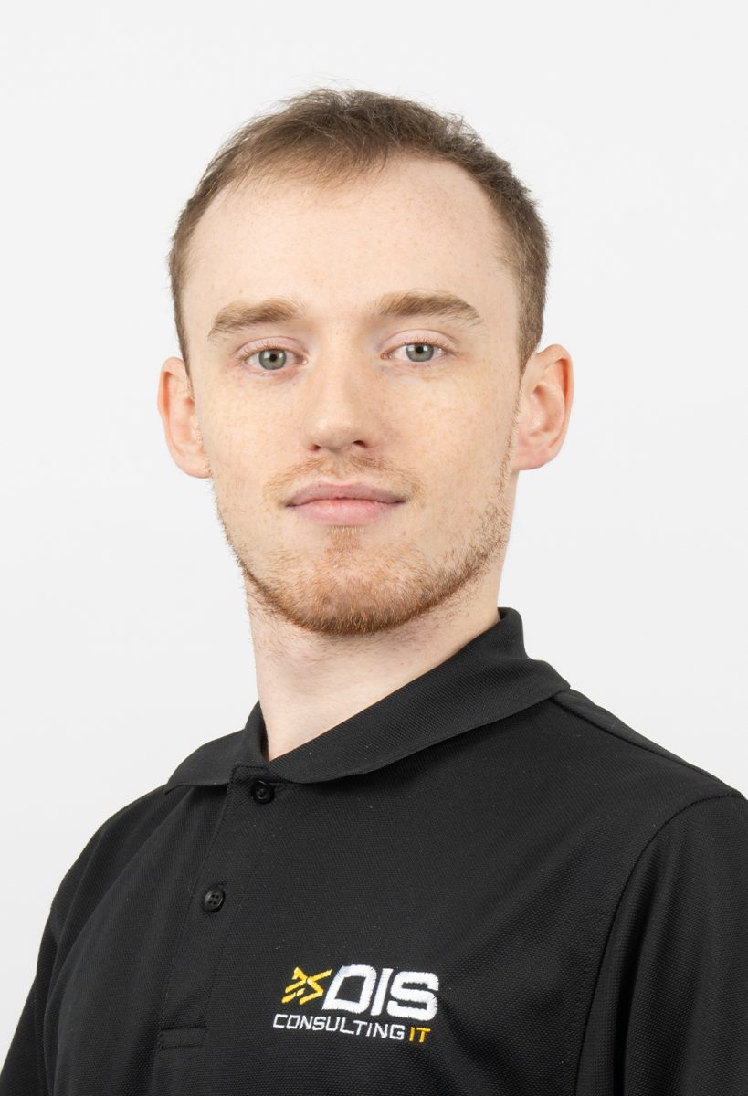 James Maslin wearing a black DIS Consulting IT polo shirt, standing against a plain light background.