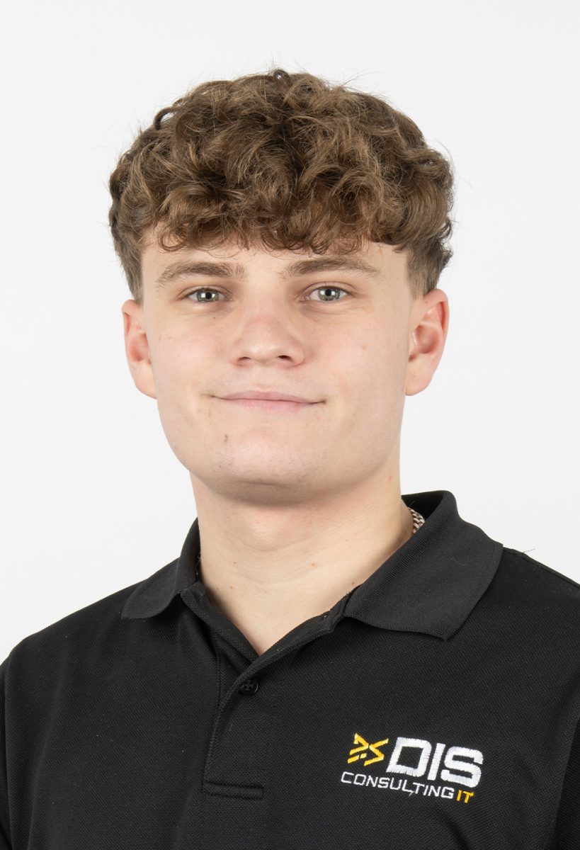 Ollie Rice, smiling, wearing a black DIS Consulting IT polo shirt, standing against a plain light background.