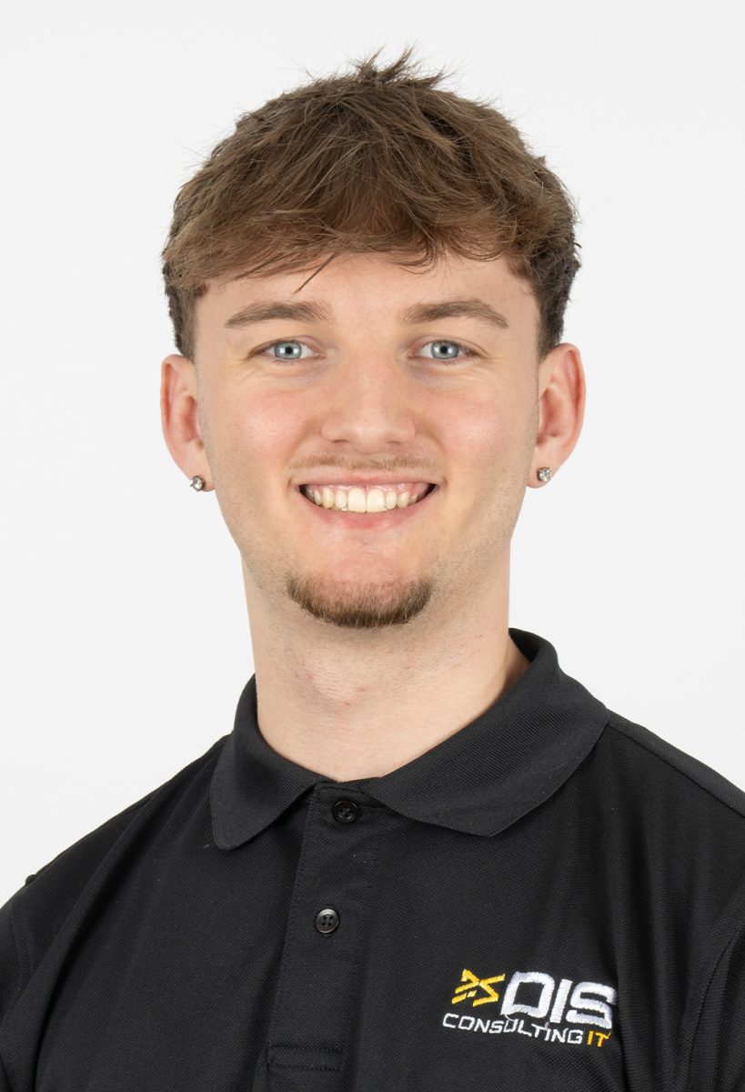 Smiling Scott Crofts wearing a black DIS Consulting IT polo shirt, standing against a plain light background.