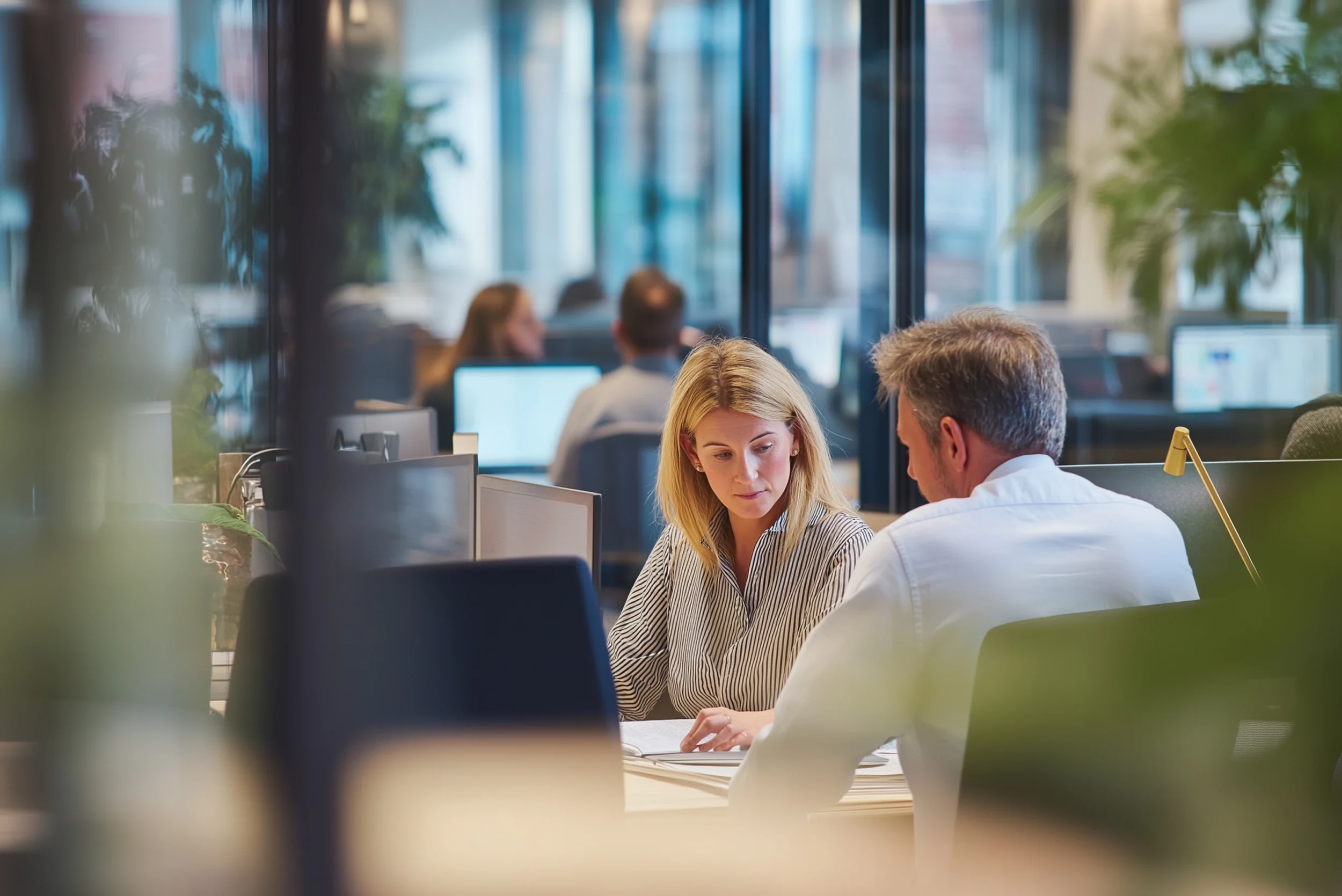 Two professionals reviewing documents together in a contemporary office workspace.