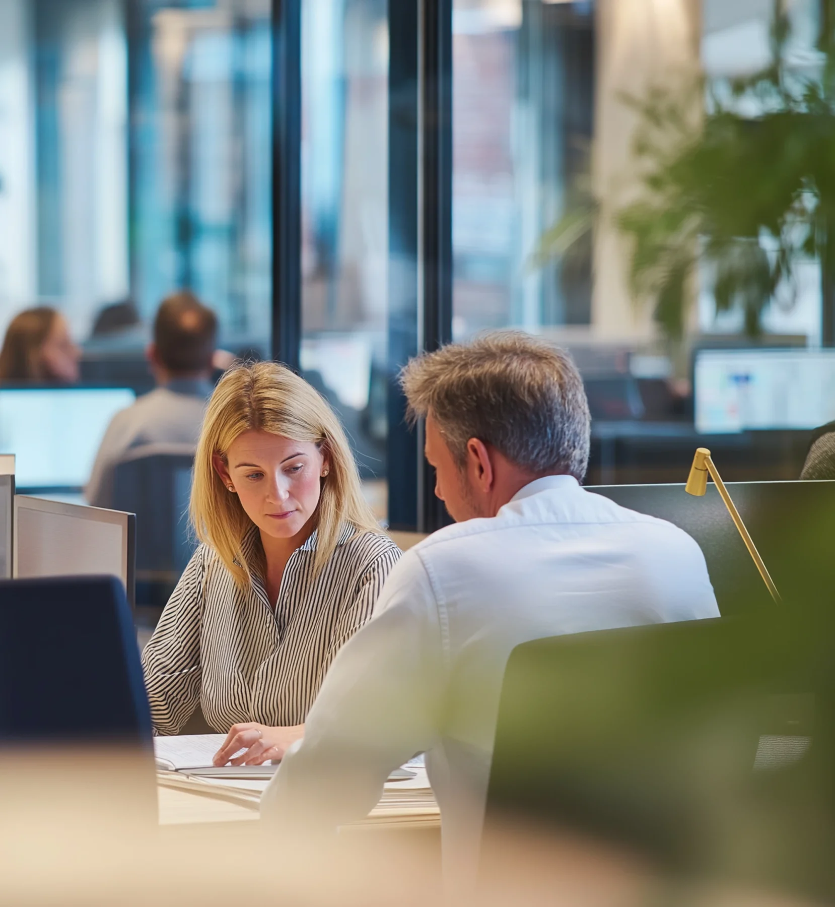 Two professionals reviewing documents together in a contemporary office workspace.