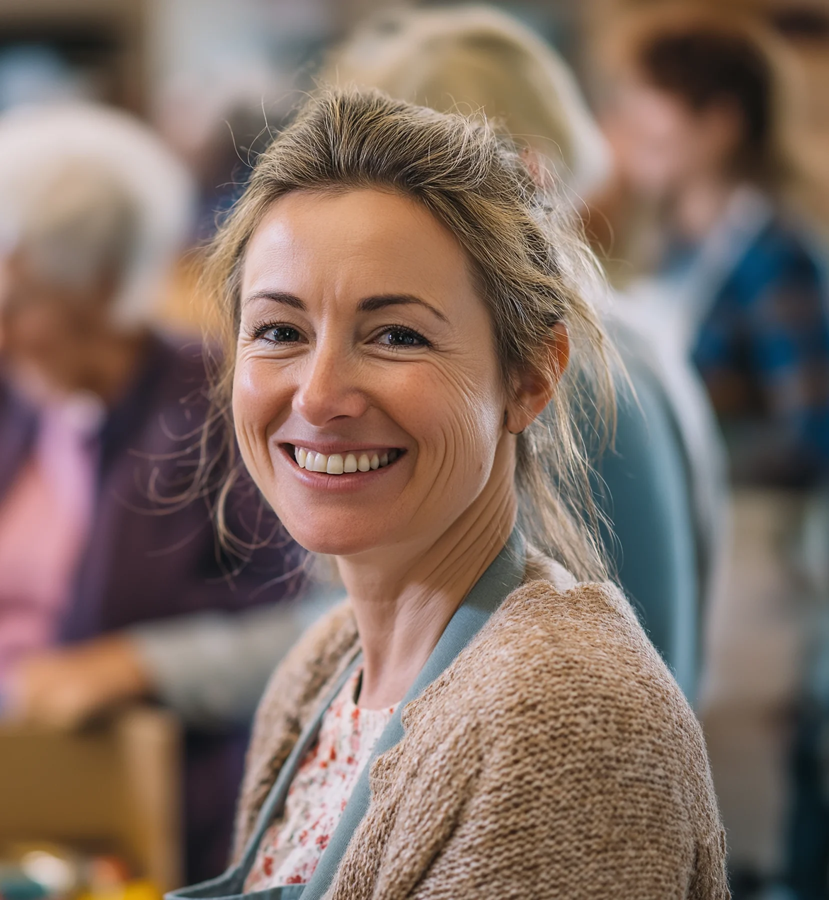 Smiling volunteer in a community centre with people working in the background.