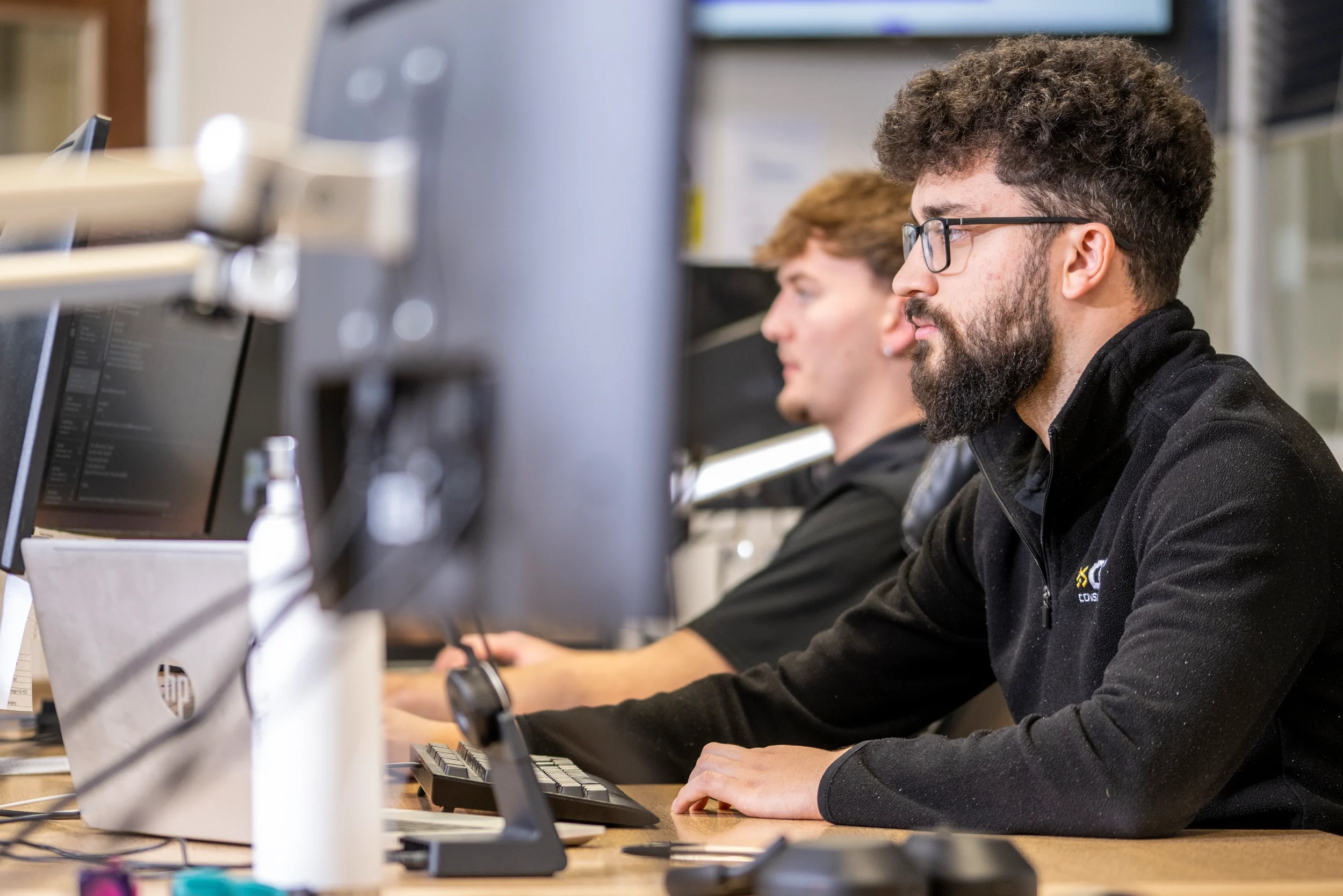 DISConsulting IT support engineers working at their desks, focused on resolving client issues while monitoring systems on multiple screens.