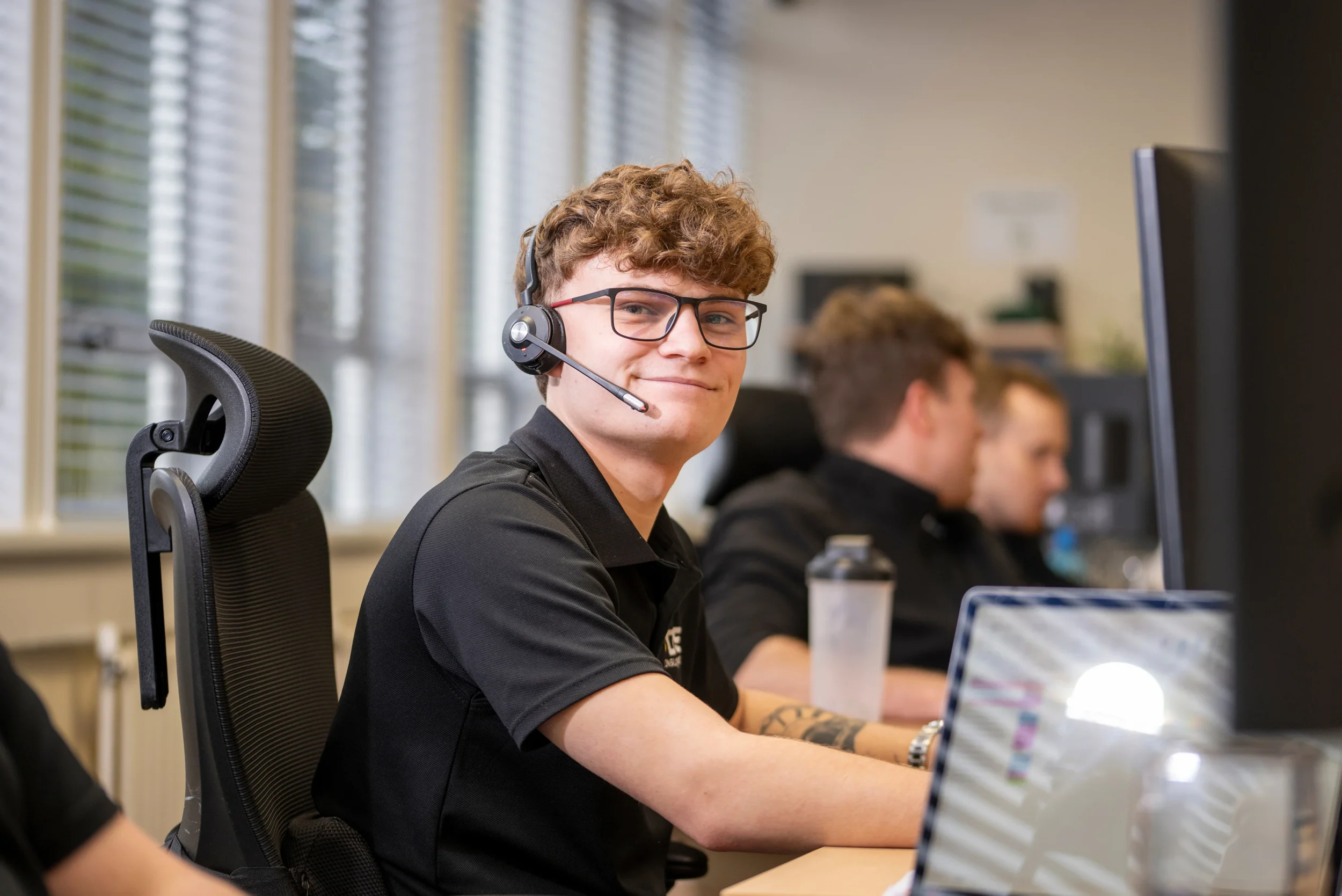 Charlie, a DISConsulting IT support engineer, smiling while wearing a headset and assisting clients from the service desk.