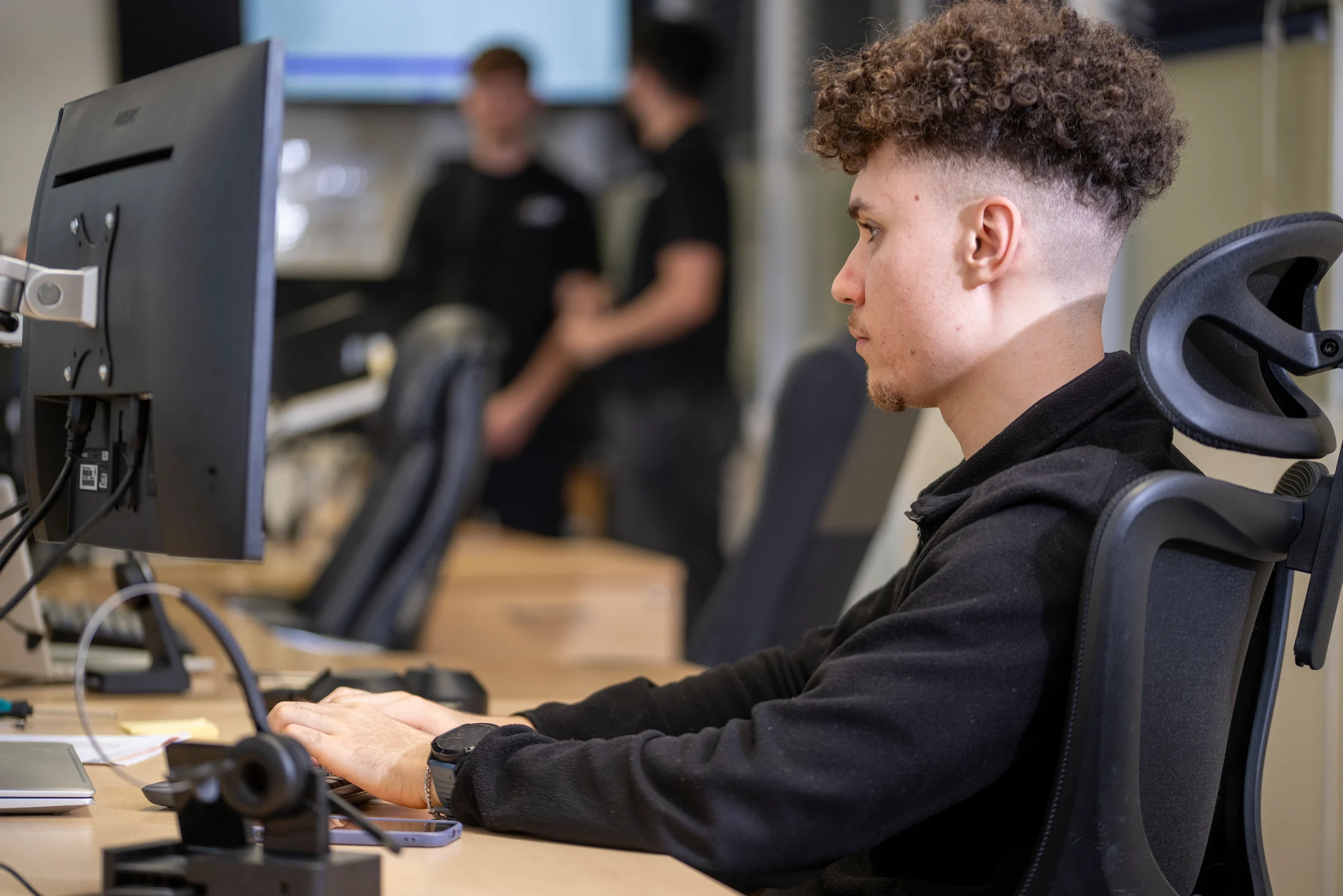 Ethan, a DISConsulting IT support engineer, working at his desk and focusing on a task while typing at a dual-monitor setup.