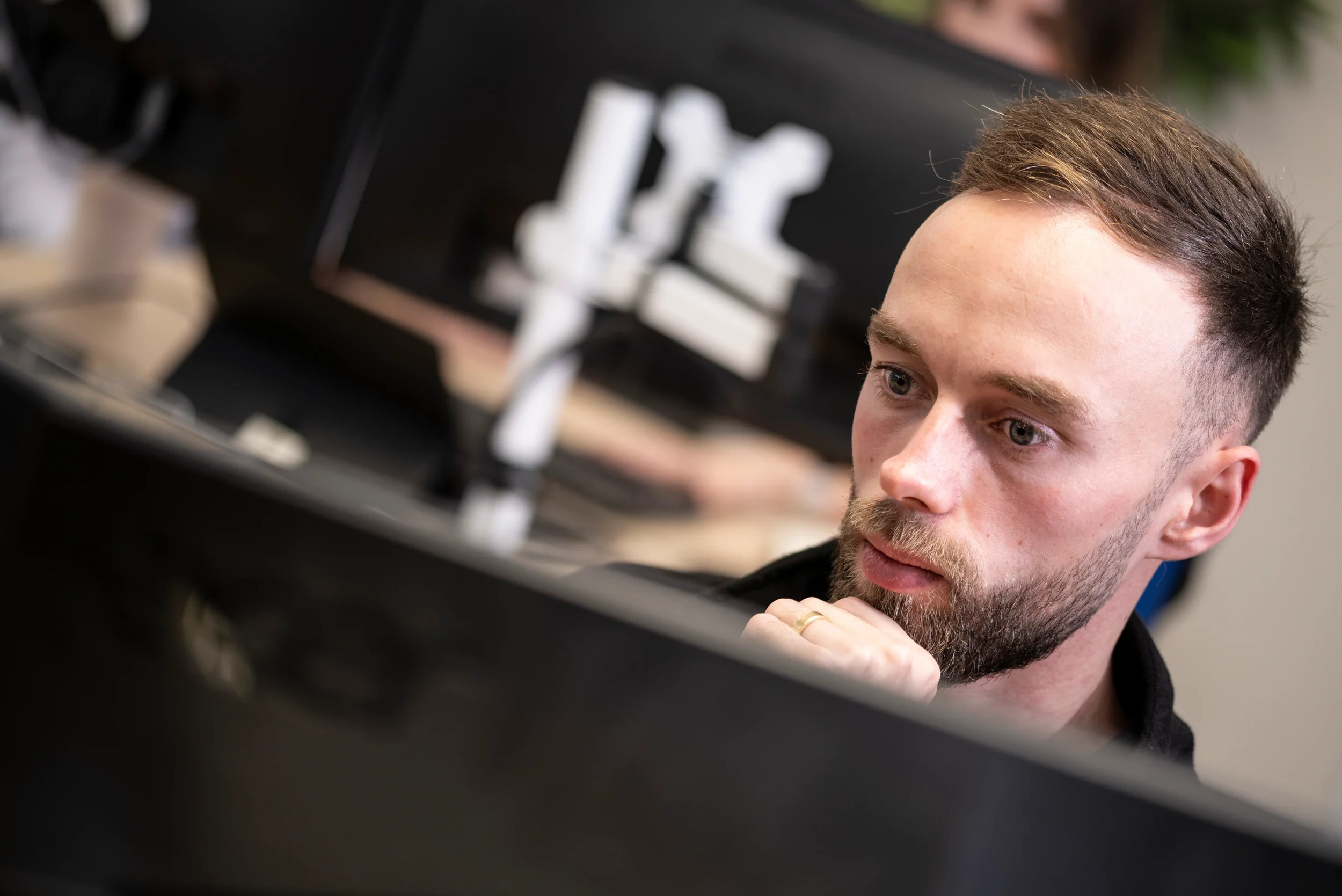 Joe, a DISConsulting IT technician, concentrating on his screen while troubleshooting at his desk in the support office.