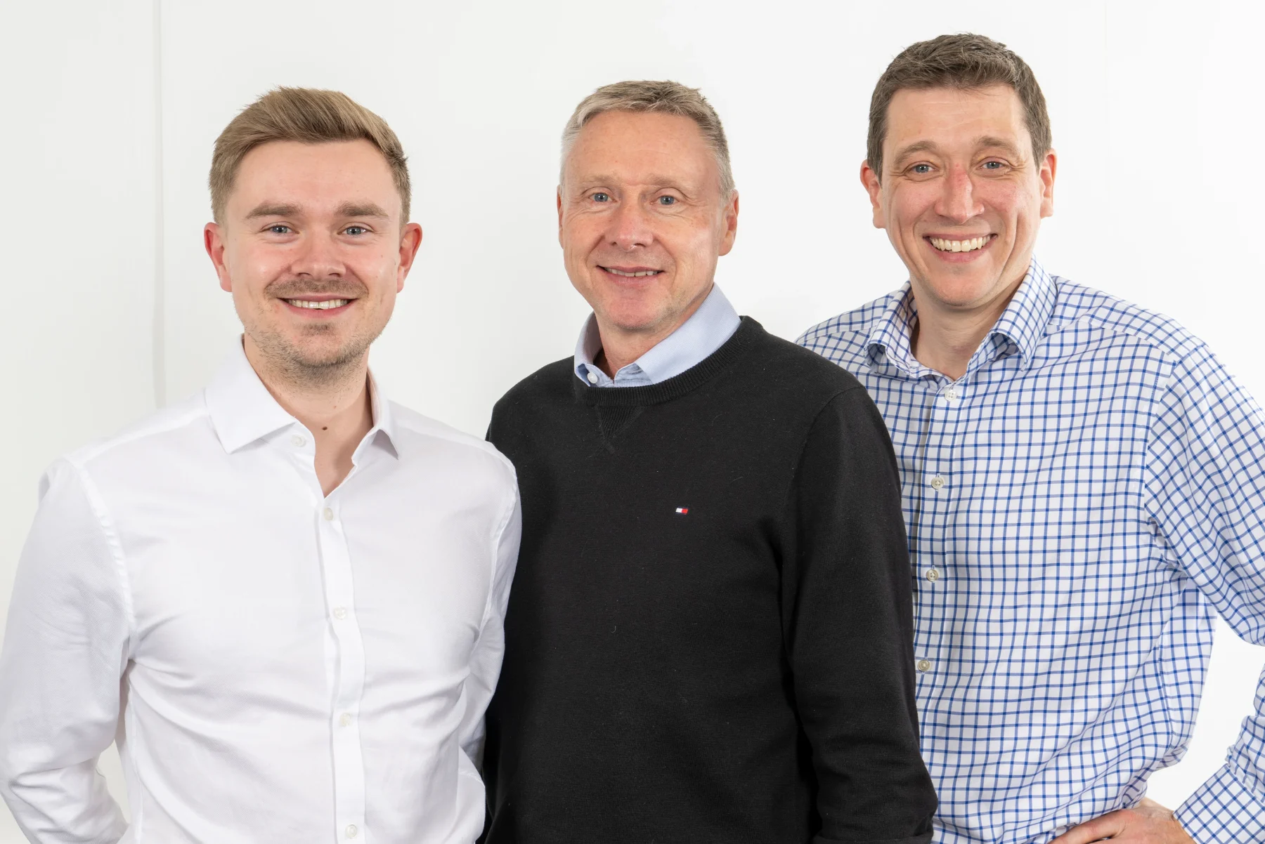 Three members of the DISConsulting leadership team smiling together in a studio setting.