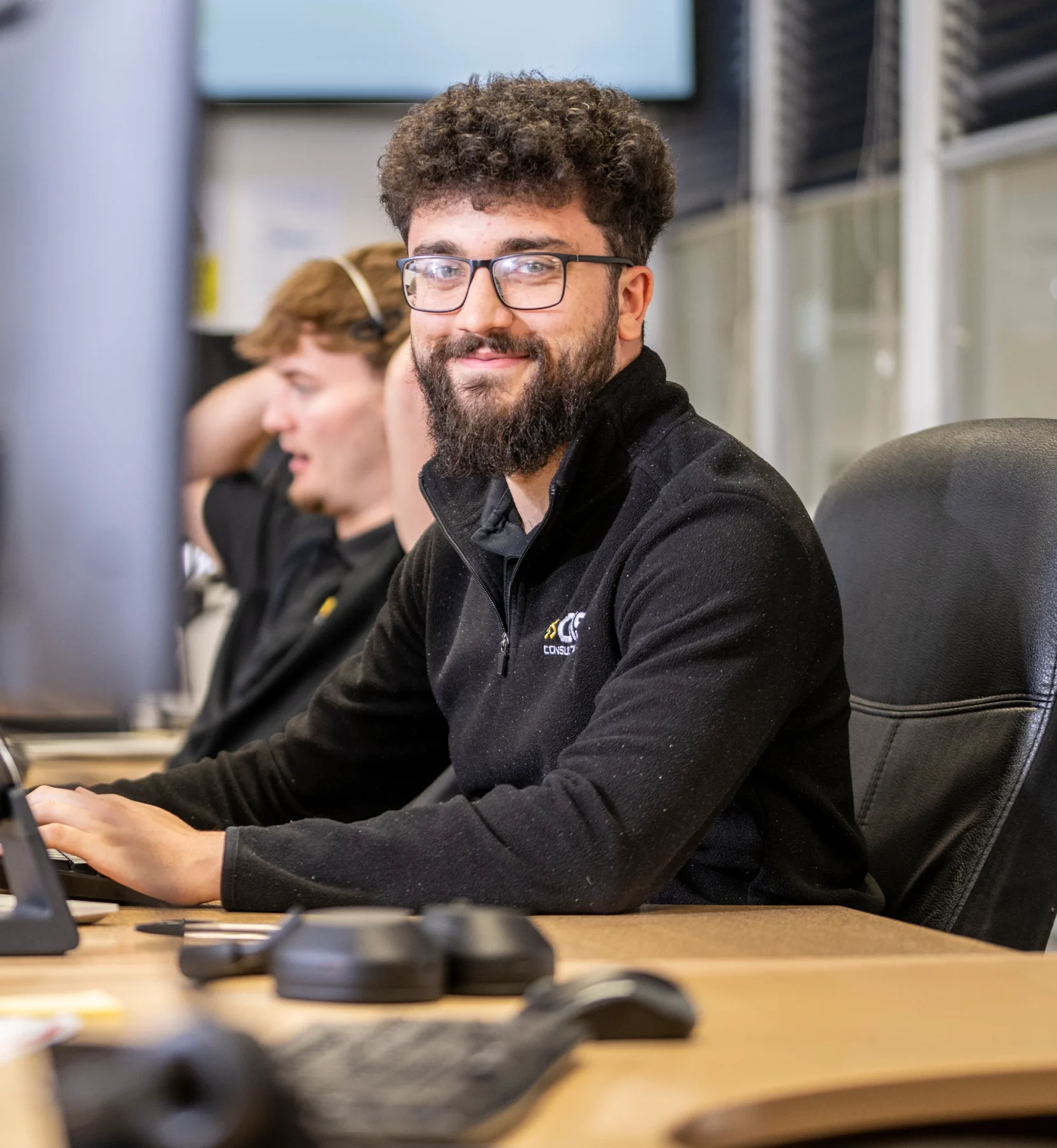 IT support engineer at DISConsulting smiling while working at his desk in the support centre.